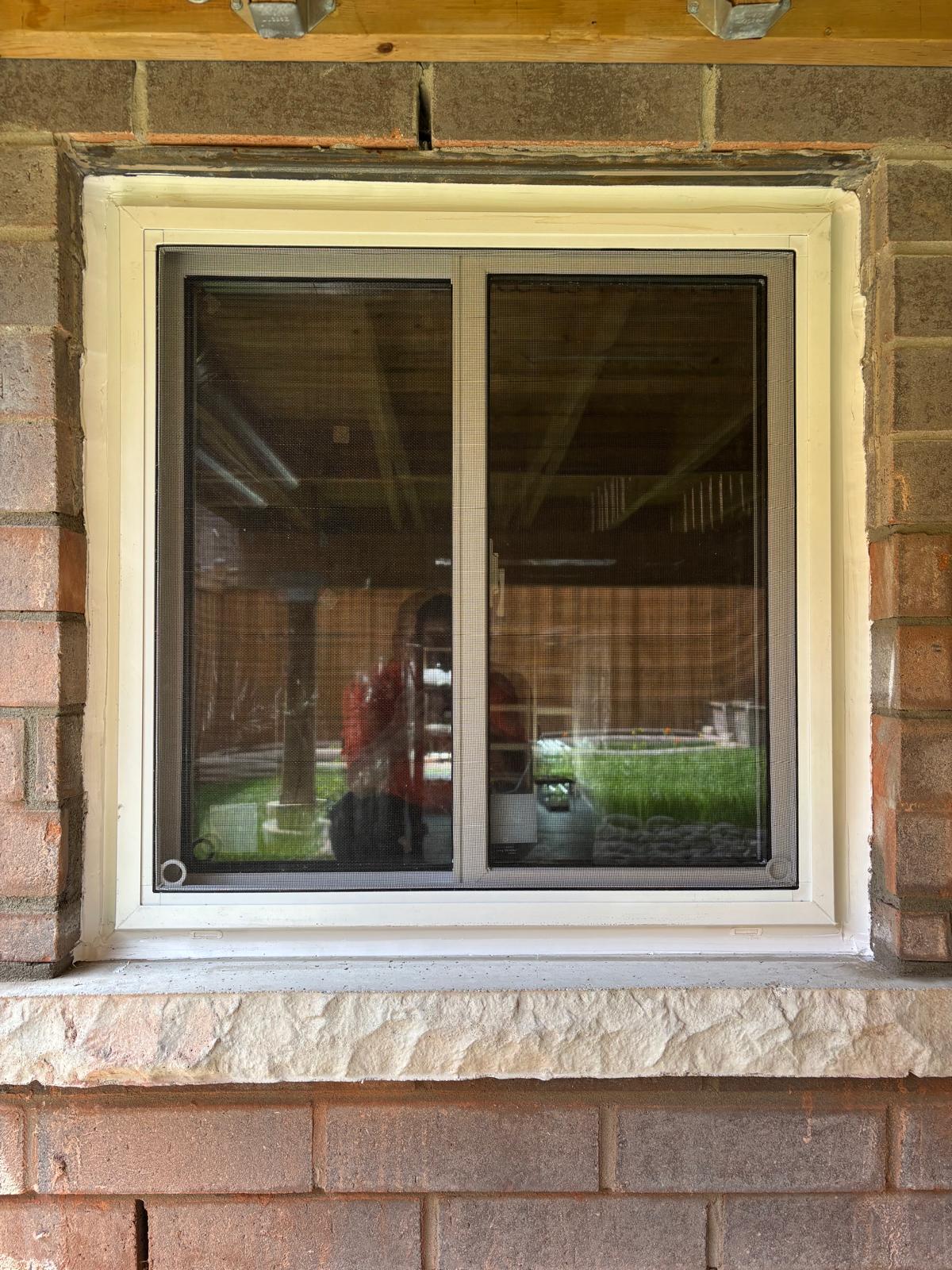 Basement slider window installed in brick foundation